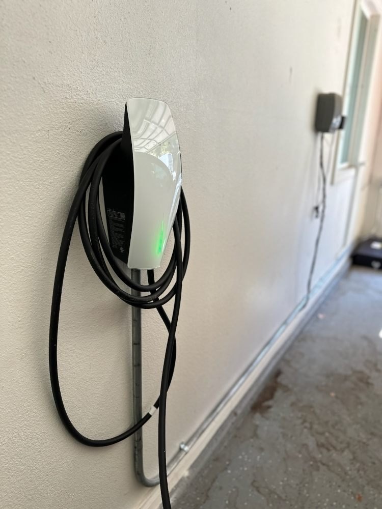 Level 2 EV charger on an exterior wall, cable wrapped on the unit