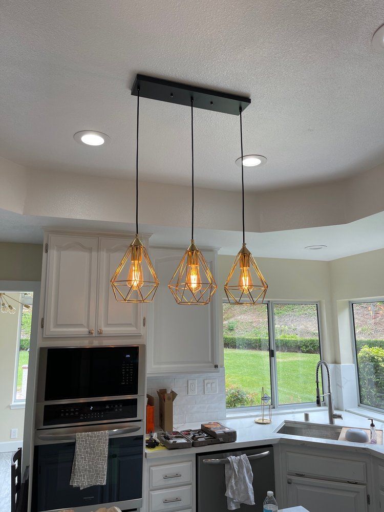 Three pendant lights and recessed lighting over a kitchen island