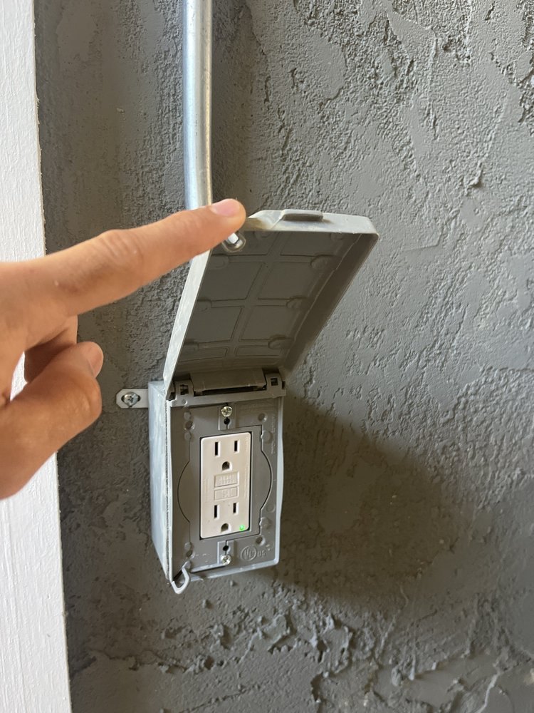 Outdoor GFCI outlet in a weatherproof box, cover open, fed by conduit