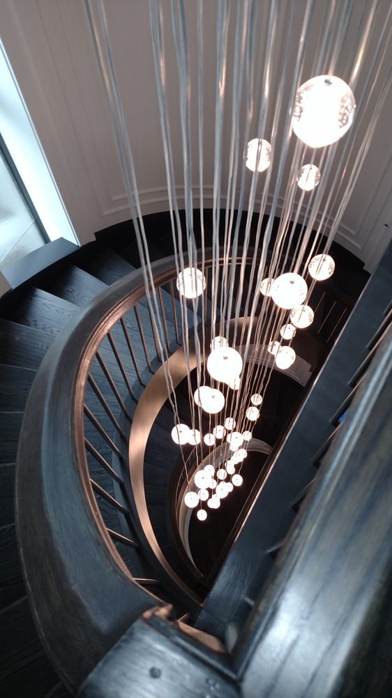 Cascading glass-sphere chandelier down a curved staircase