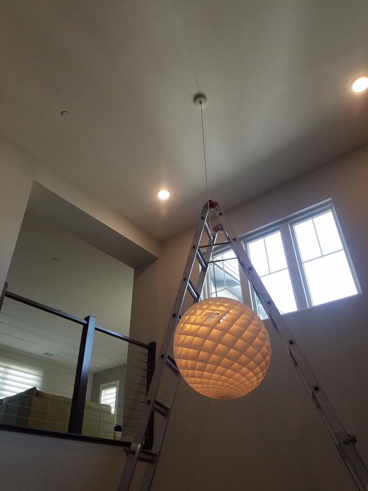Single pendant hung in a two-story stairwell with recessed lighting