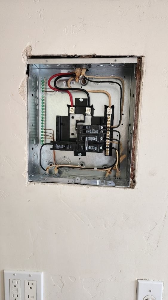 Flush-mounted sub-panel opened for inspection, older wiring