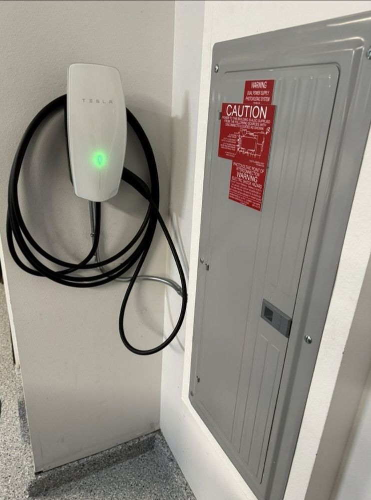 Tesla Wall Connector installed next to the main panel in a garage