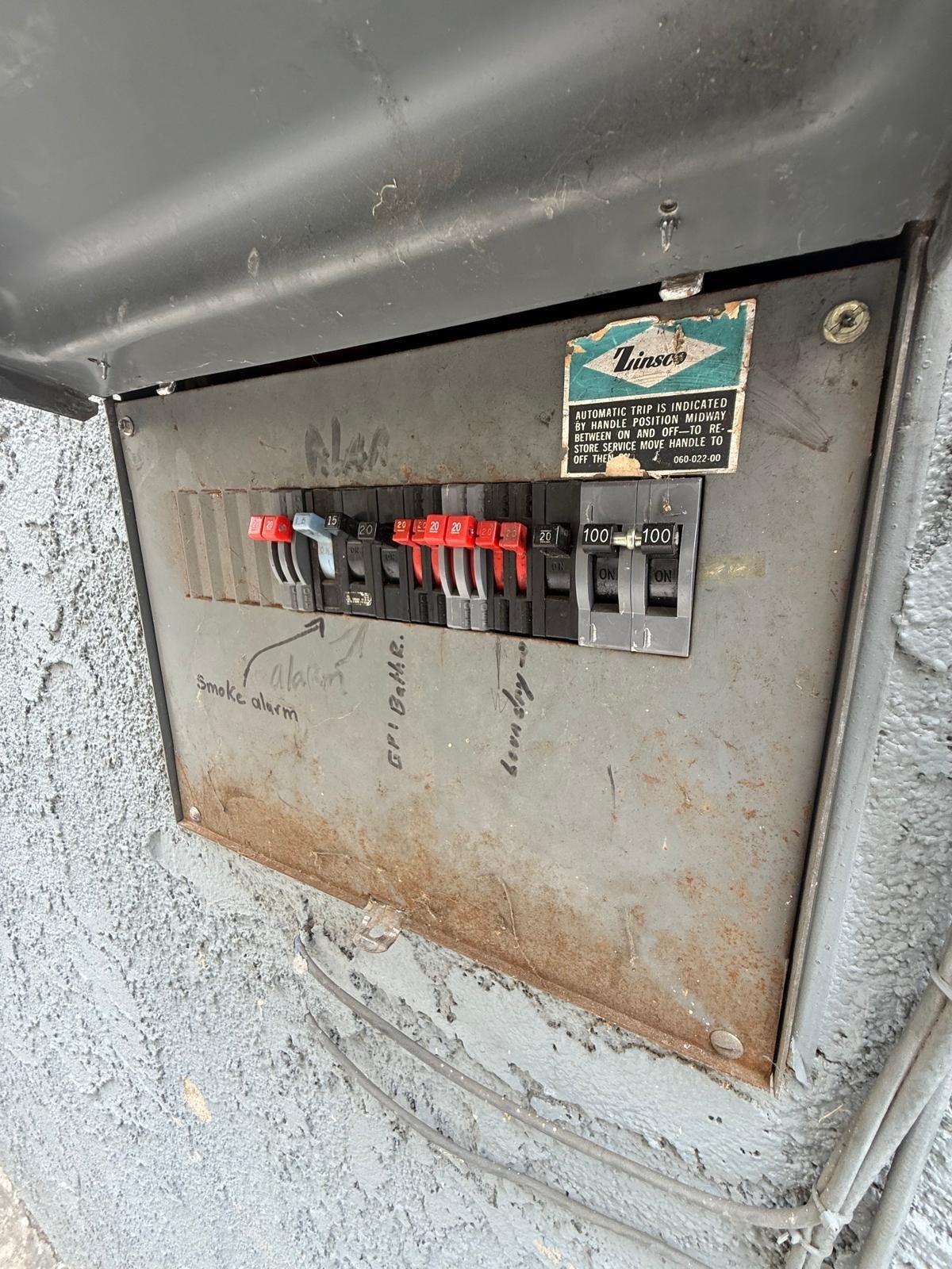 Original Zinsco panel with a rusted cover and hand-written labels